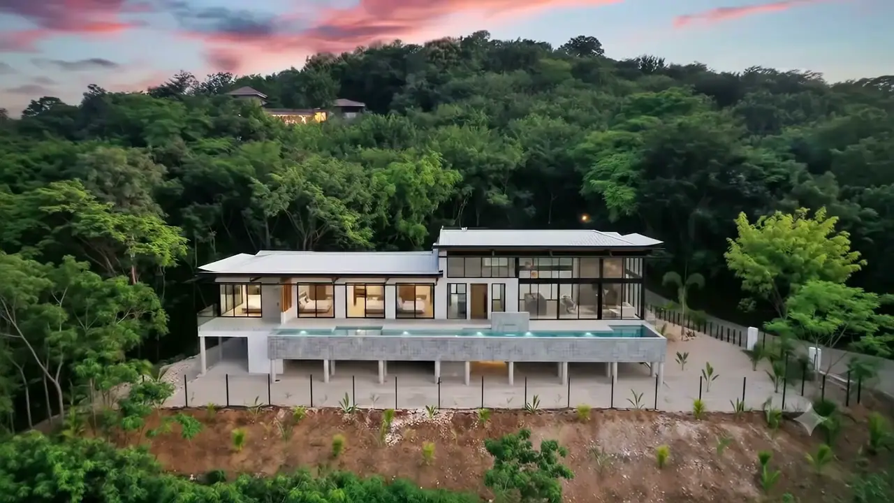 Aerial view of a modern home with a pool surrounded by tropical forest