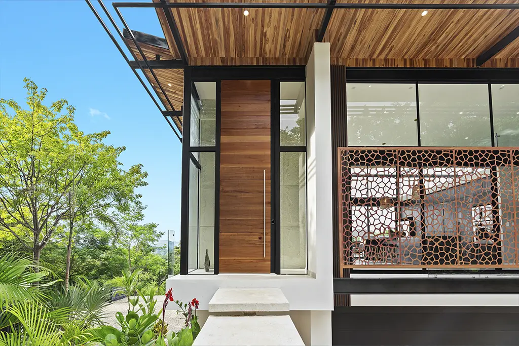 Entrada de una casa contemporánea en Costa Rica con fachada de madera y vidrio